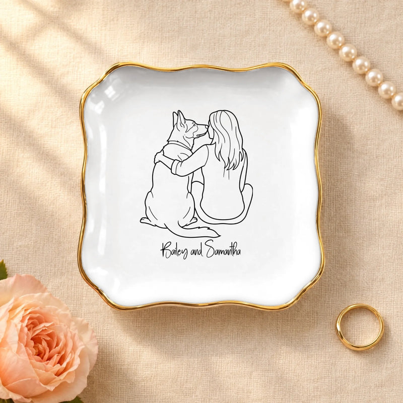 Personalized line drawing of a woman and her dog on a wavy square ceramic ring dish with gold rim