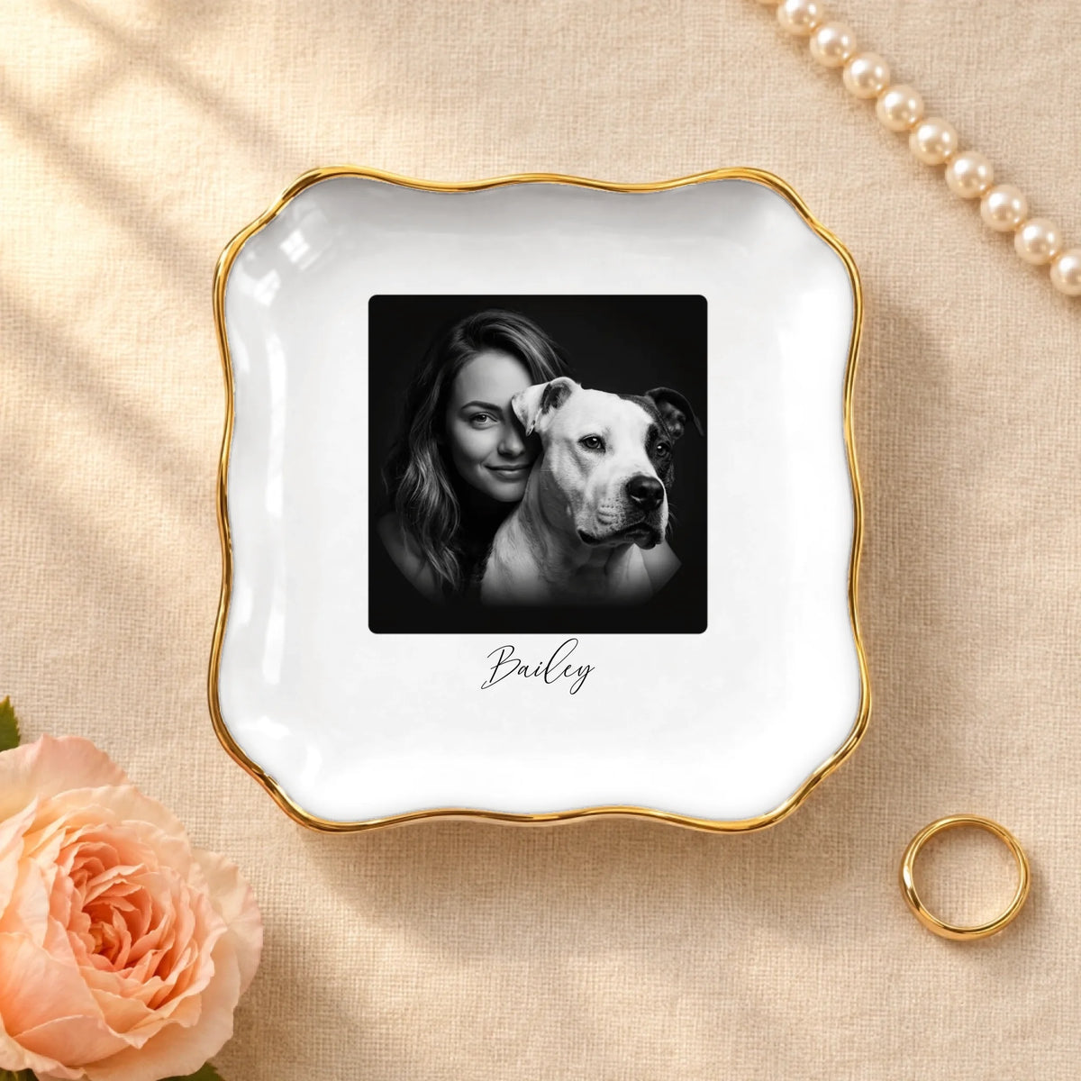 Black and white studio portrait of owner and pet on a wavy square ceramic ring dish with gold rim