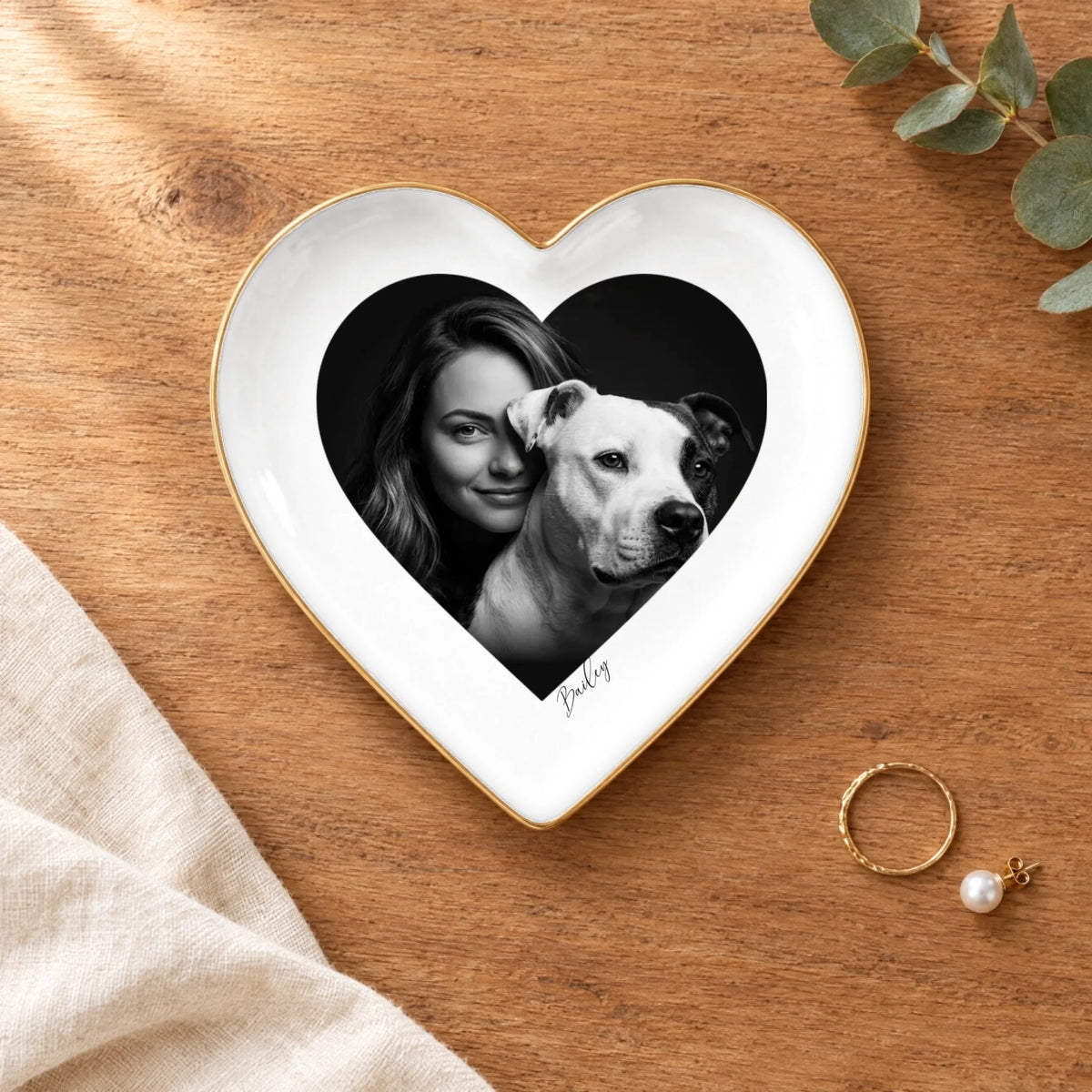 Black and white studio portrait heart ring dish on a wooden table with linen and eucalyptus