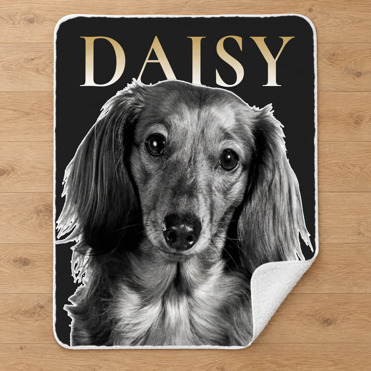 Personalized black and white pet portrait sherpa blanket with name, laid flat on an oak floor
