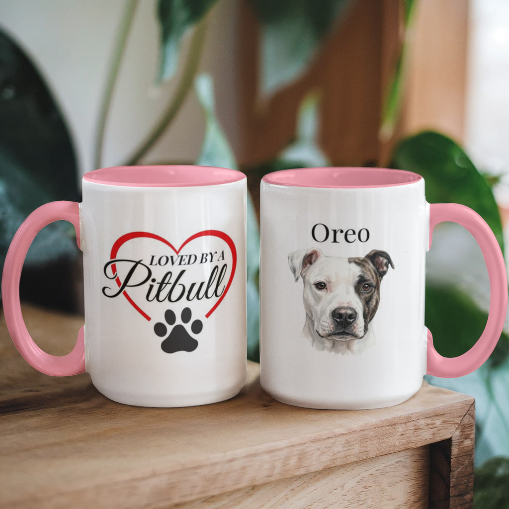 Two mugs with pink handles on a wooden surface, one featuring a heart and paw print design, the other with a dog's name 'Oreo'.