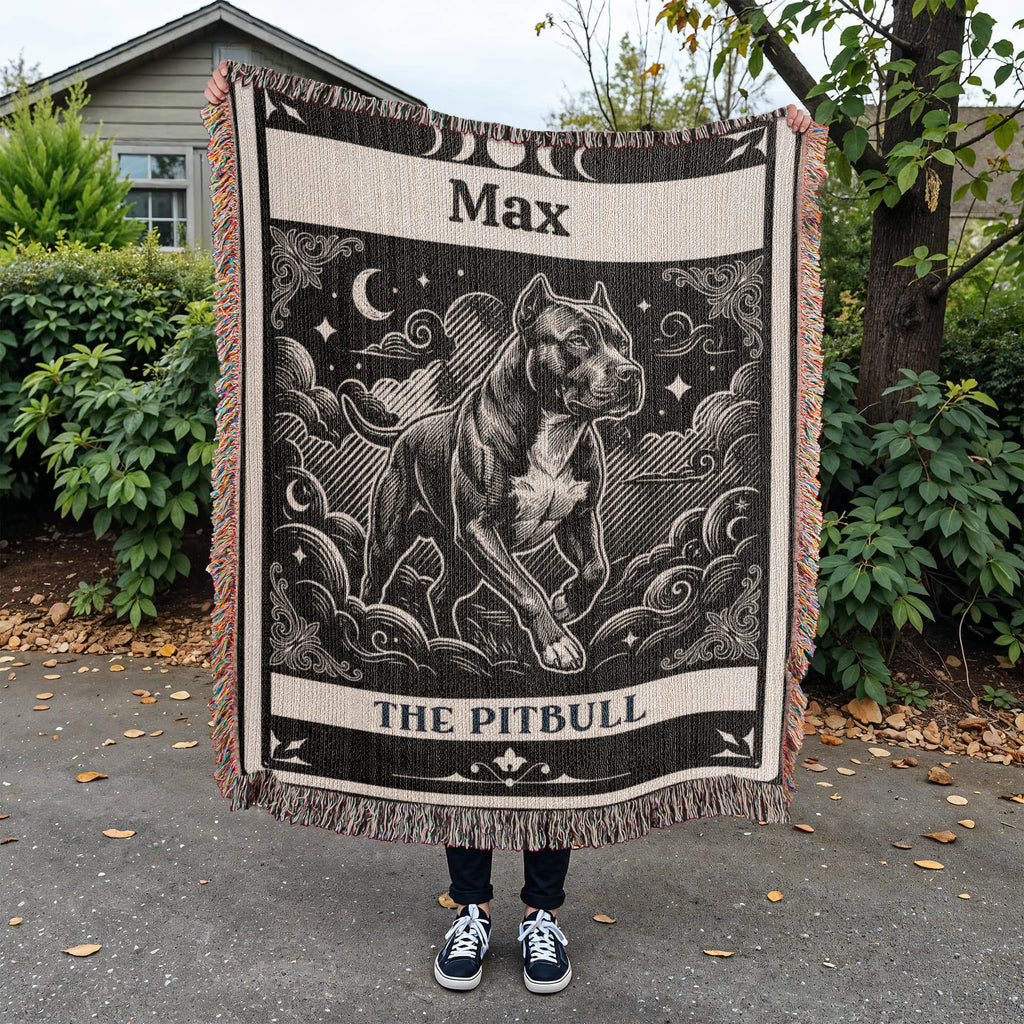 Person holding a blanket with a tarot card graphic of a pitbull dog and text 'Max The Pitbull' outdoors.