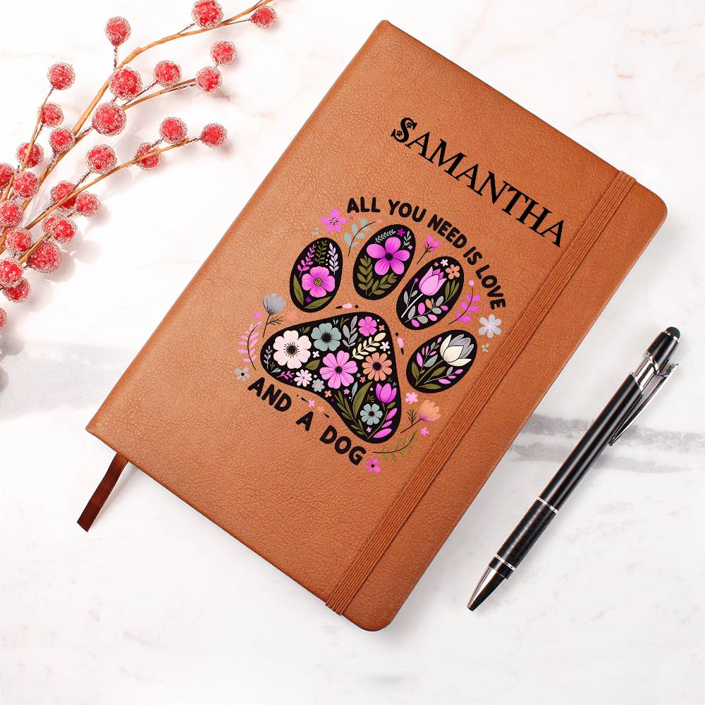 Brown notebook with floral paw design and text 'All you need is love and a dog' on a white background.