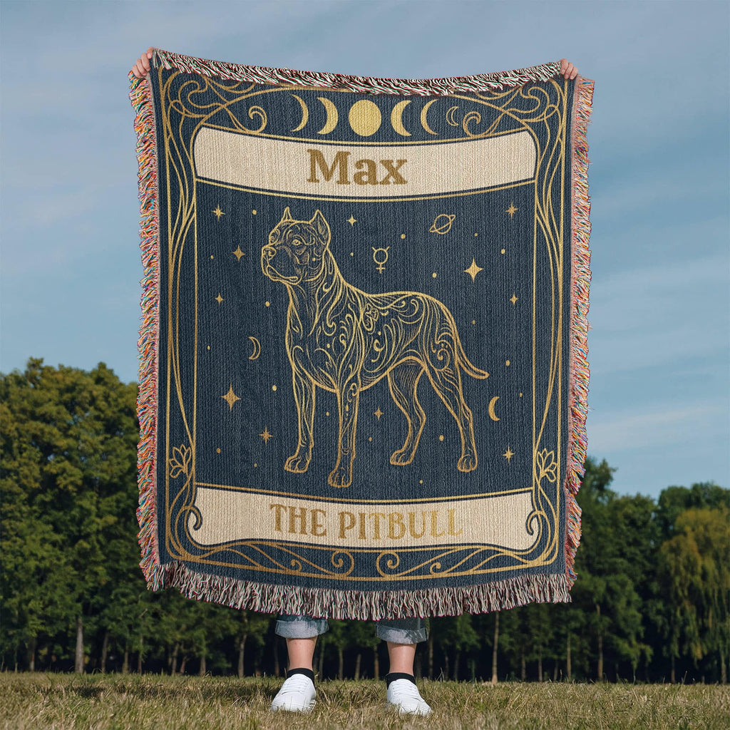 Person holding a decorative woven blanket with a tarot card dog design and personalized with the name 'Max' printed on it, outdoors.