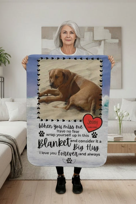 Person holding a blanket with a dog picture and text in a living room.