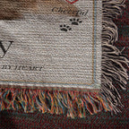 Textured fabric with fringes and printed text, featuring a paw print design on a woven blanket.