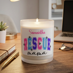 Candle with 'Samantha RESCUE mama' label on a desk with laptop and notebook.