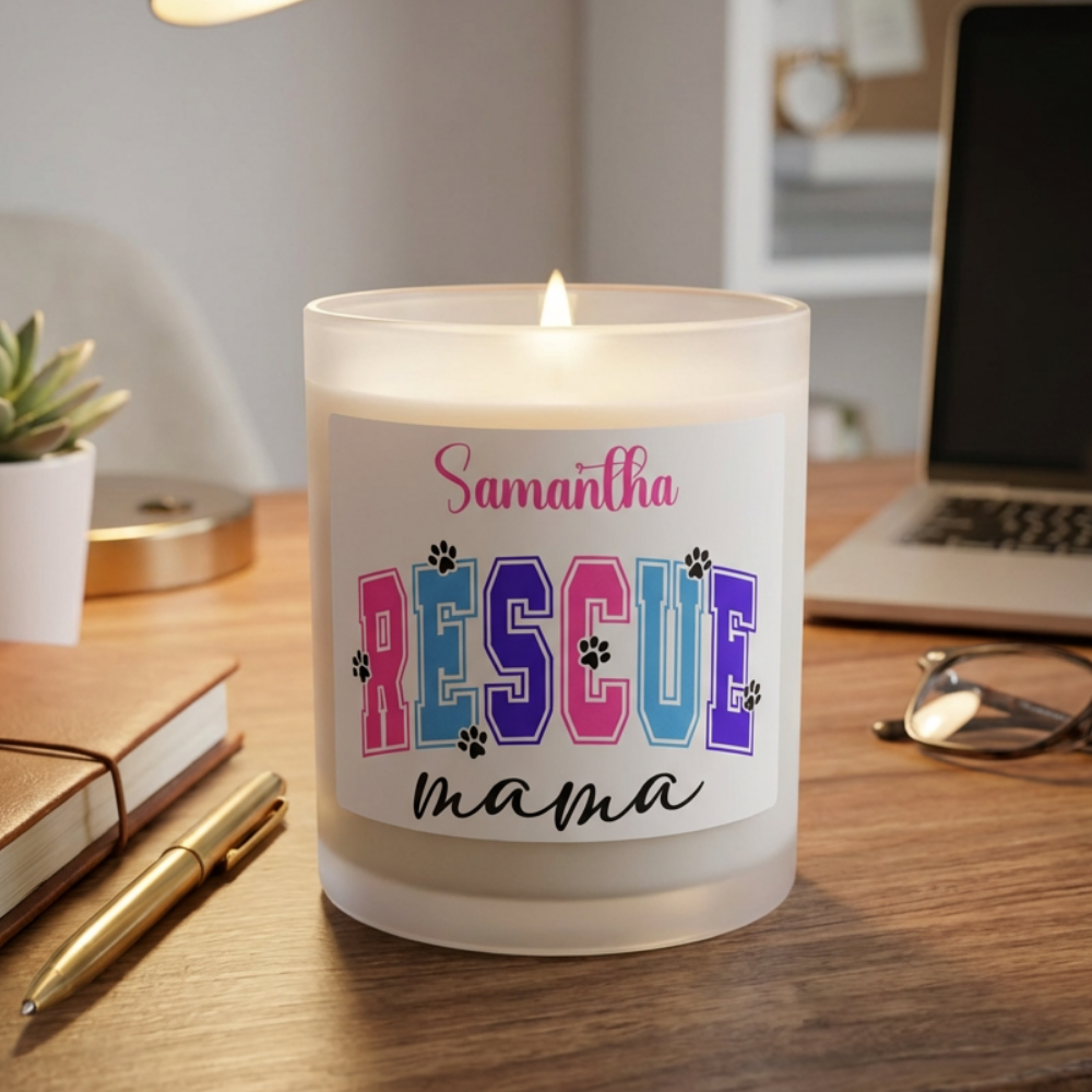 Candle with 'Samantha RESCUE mama' label on a desk with laptop and notebook.