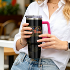 Person holding a black tumbler with a pink handle in an indoor setting