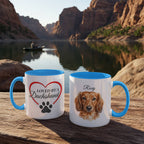 Two mugs with blue interior and handle on a wooden surface with a scenic background of a lake and mountains.