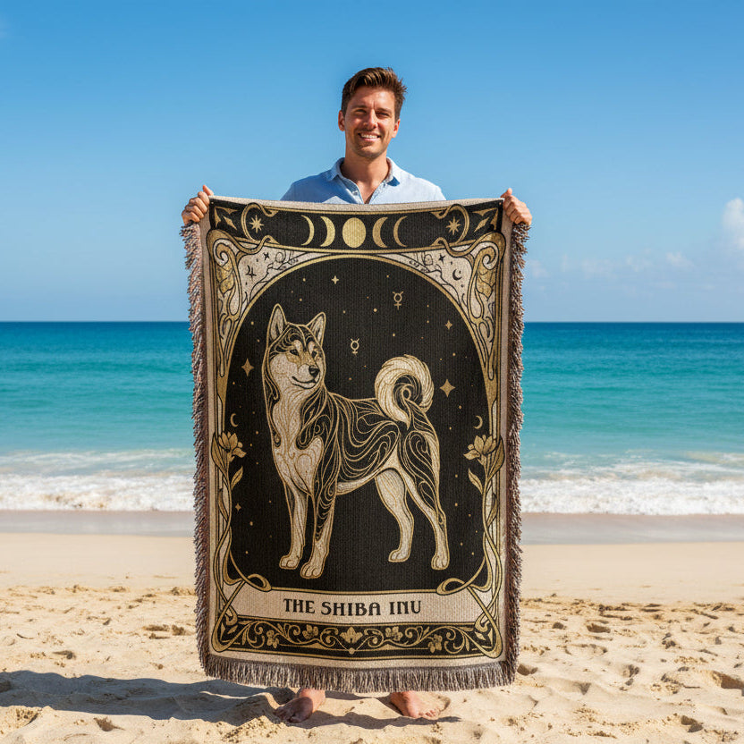Man holding a Shiba Inu-themed blanket on a beach with ocean in the background