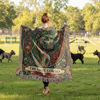 Person holding a decorative blanket with a dog design in a park with dogs.
