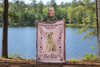A woman holding a pink Labrador Retriever blanket with the name 'Bella' in a garden setting. Personalize your woven blanket with your favorite Labrador's photo and Name.