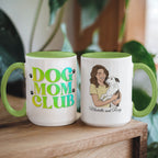 Two mugs with 'Dog Mom Club' text and a illustration of a woman holding a dog on a wooden surface.