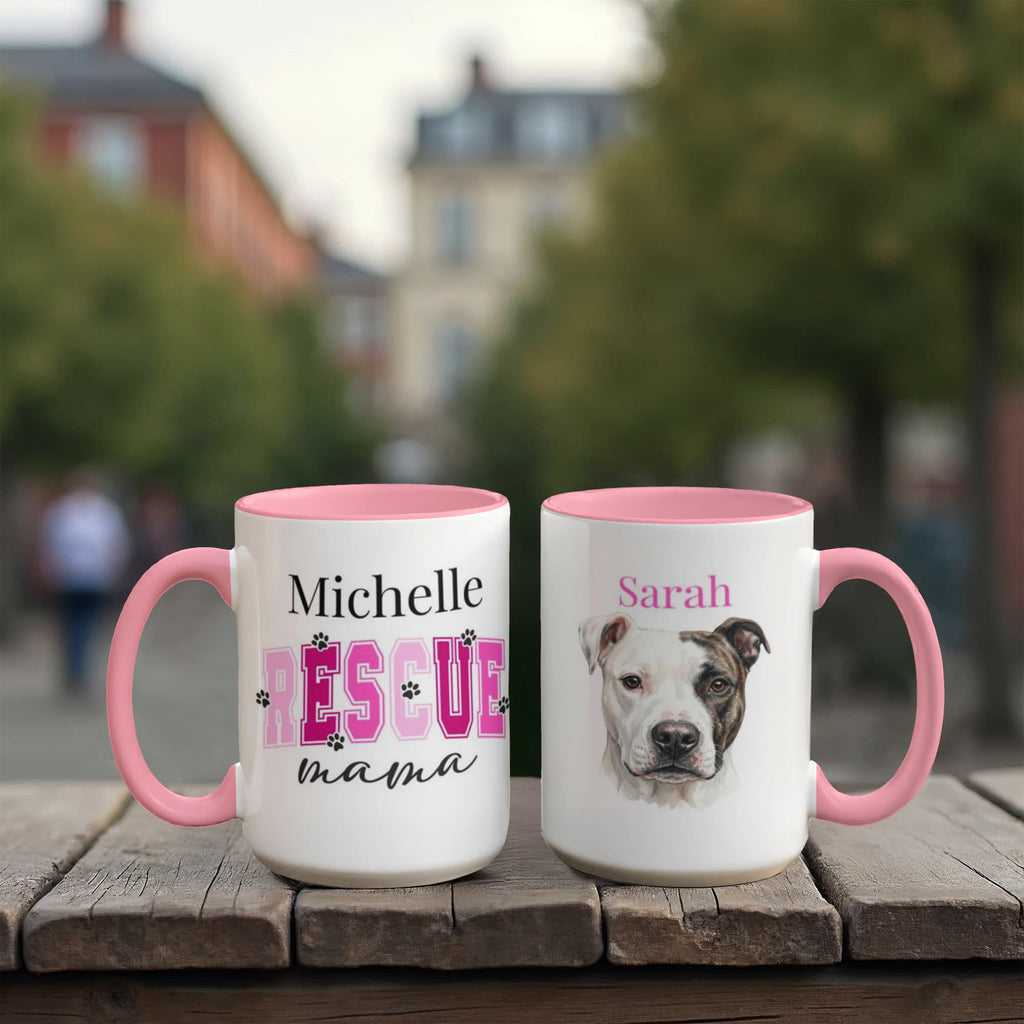 Two mugs with pink handles on a wooden surface, one featuring text and the other with a dog's face.