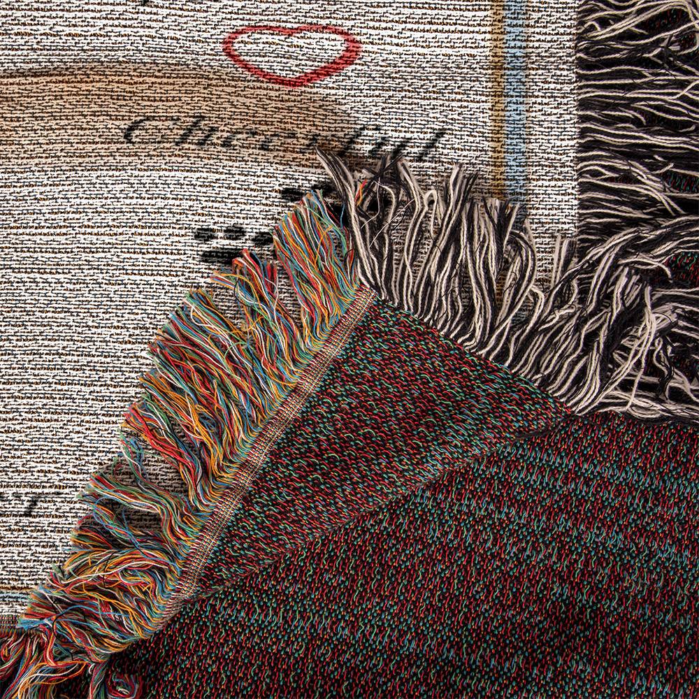 Close-up of a textured fabric with colorful fringes and a blurred background on a woven blanket.