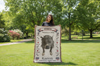 Woman holding a blanket with a pitbull design and text outdoors. Personalize your woven blanket with your favorite picture of your Pittie with their name.