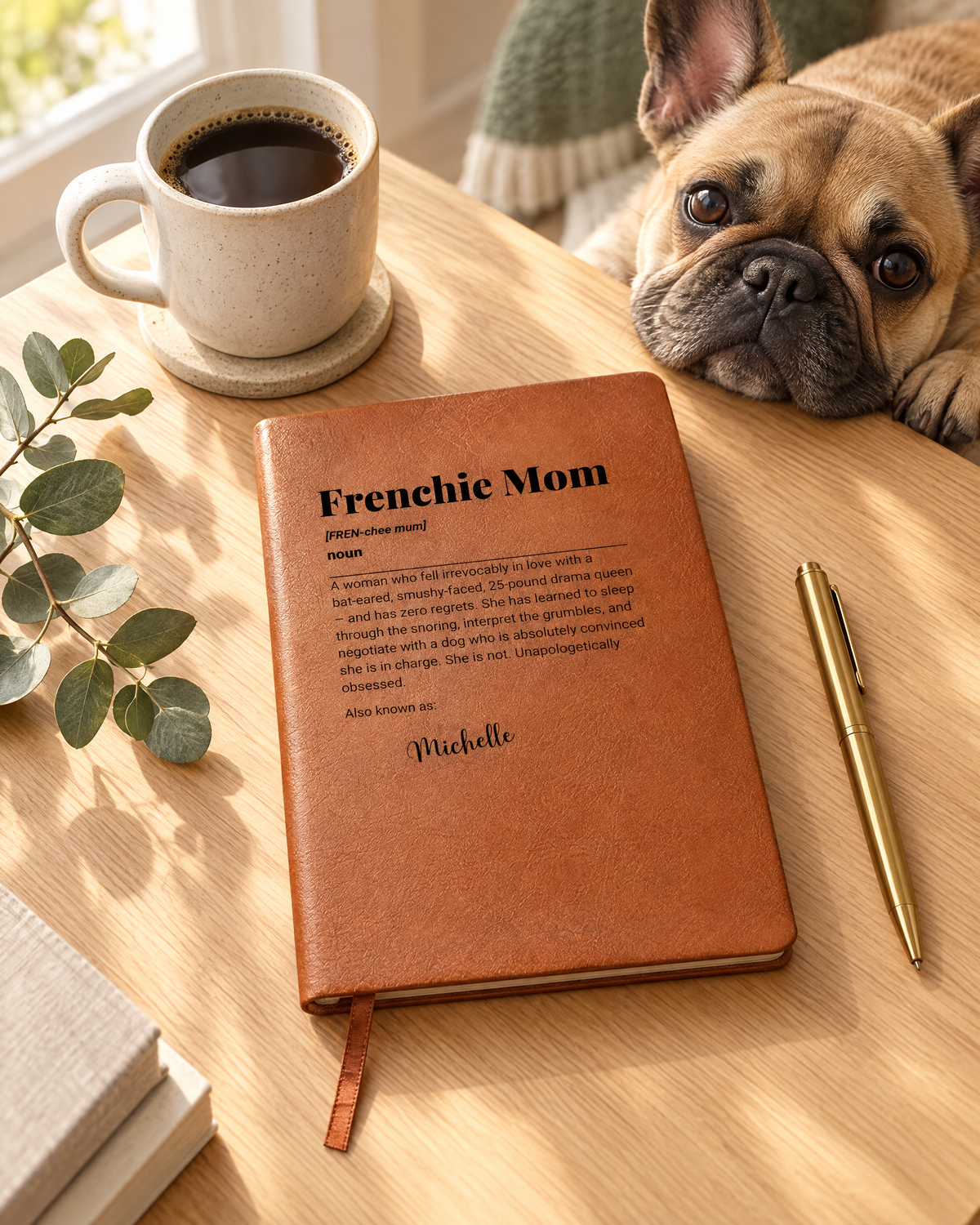 Personalized Frenchie Mom leather journal on a desk with coffee while a French bulldog looks on